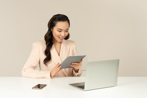 Азиатский женский офисный работник, глядя на планшет