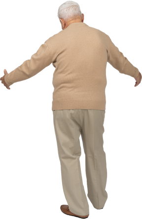 Rear view of an old man in casual clothes standing with outstretched arms