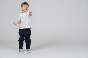 Niño pequeño con ropa informal apuntando hacia adelante