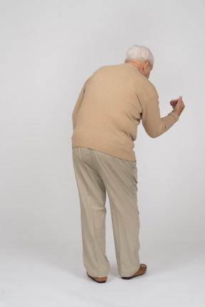 Rear view of an old man in casual clothes explaining something