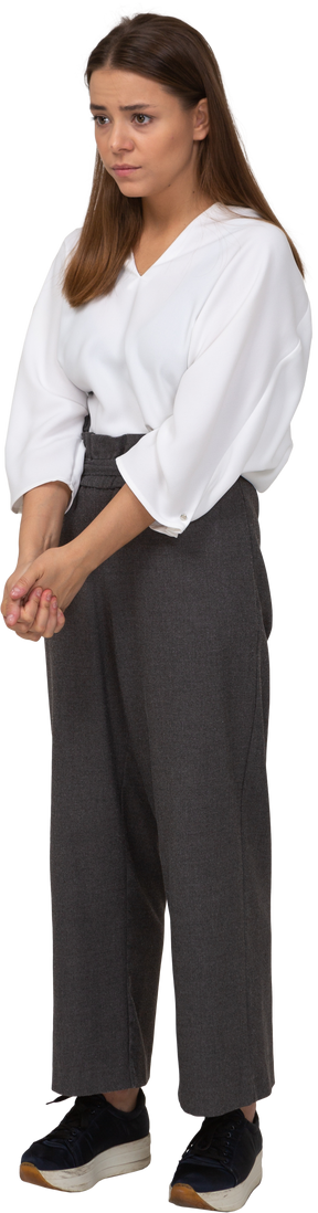 Three-quarter view of a sad young lady in office clothing holding hands together