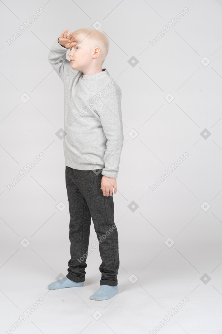Vista lateral de um menino segurando a mão sobre os olhos