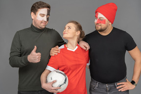 A portrait of two football male fans with female soccer player