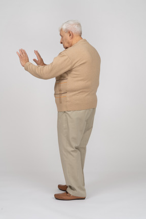 Seitenansicht eines alten mannes in freizeitkleidung, der eine stoppgeste zeigt