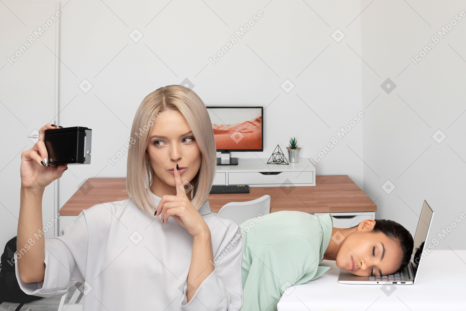 A woman taking a picture with a woman asleep on a laptop