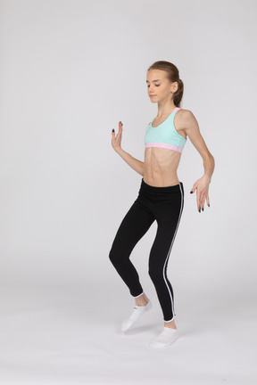 Девушка в спортивной одежде в полный рост машет руками и танцует