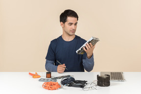 A young man in casual blue clothes working with computer details