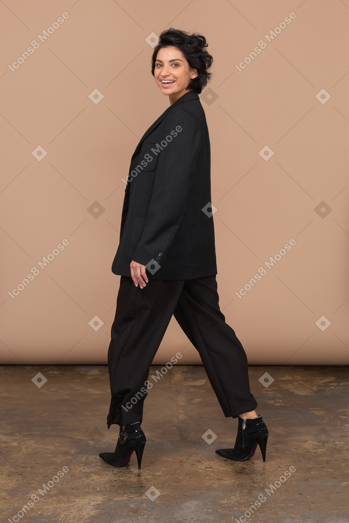 Side view of a happy businesswoman stepping aside and smiling while looking at camera