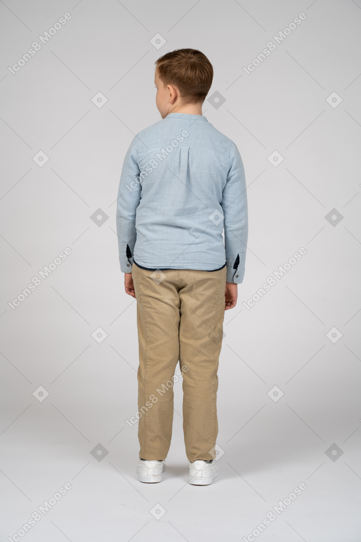 Vista traseira de um menino em roupas casuais, olhando de lado