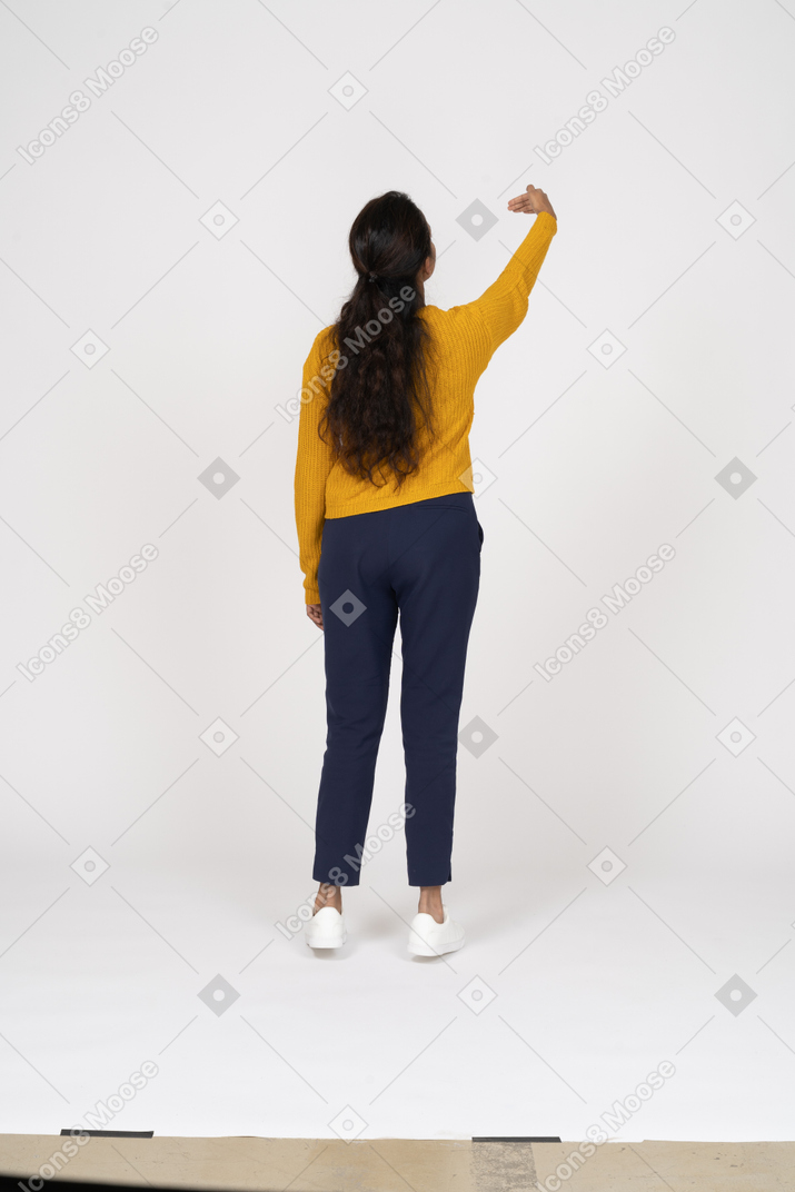 一个穿着休闲服的女孩举起手臂站立的后视图