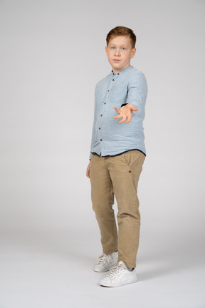 Vista frontal de um menino em roupas casuais em pé com o braço estendido