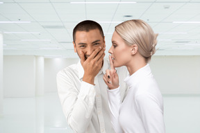 Man holding back laughter and woman hushing him