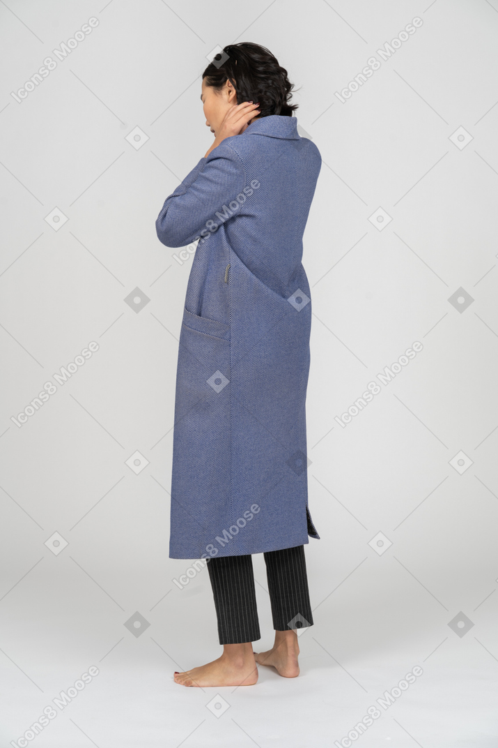 Vista posteriore di una donna in cappotto con la mano sul collo