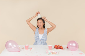 Giovane donna asiatica che regola il cono di compleanno sulla sua testa