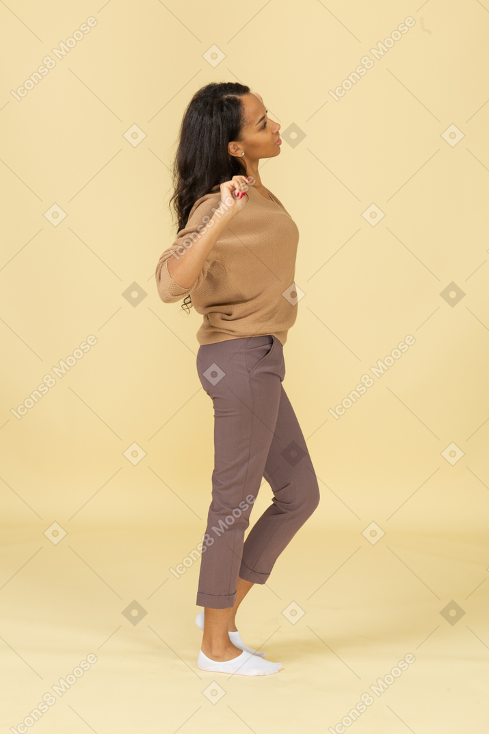 Vista lateral de una mujer joven de piel oscura soñolienta estirando su espalda