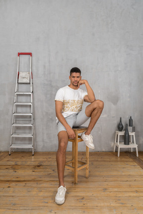 Young man sitting and resting his elbow on his knee