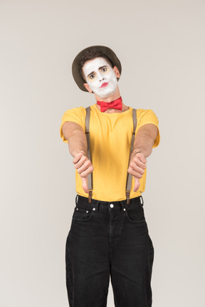 Sad looking male clown showing thumbs down with both hands