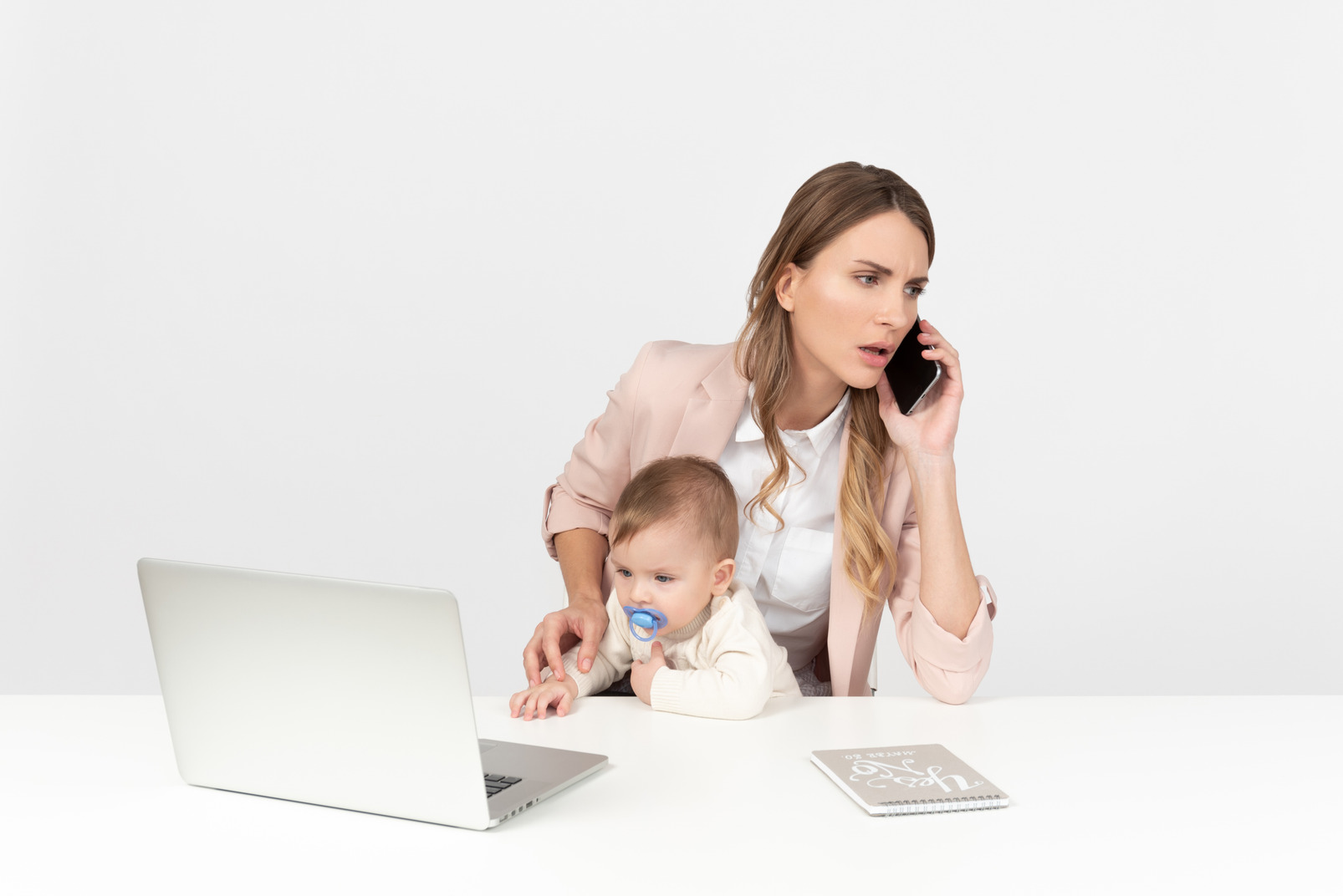 Young mom working on computer, talking on the phone and looking after a kid