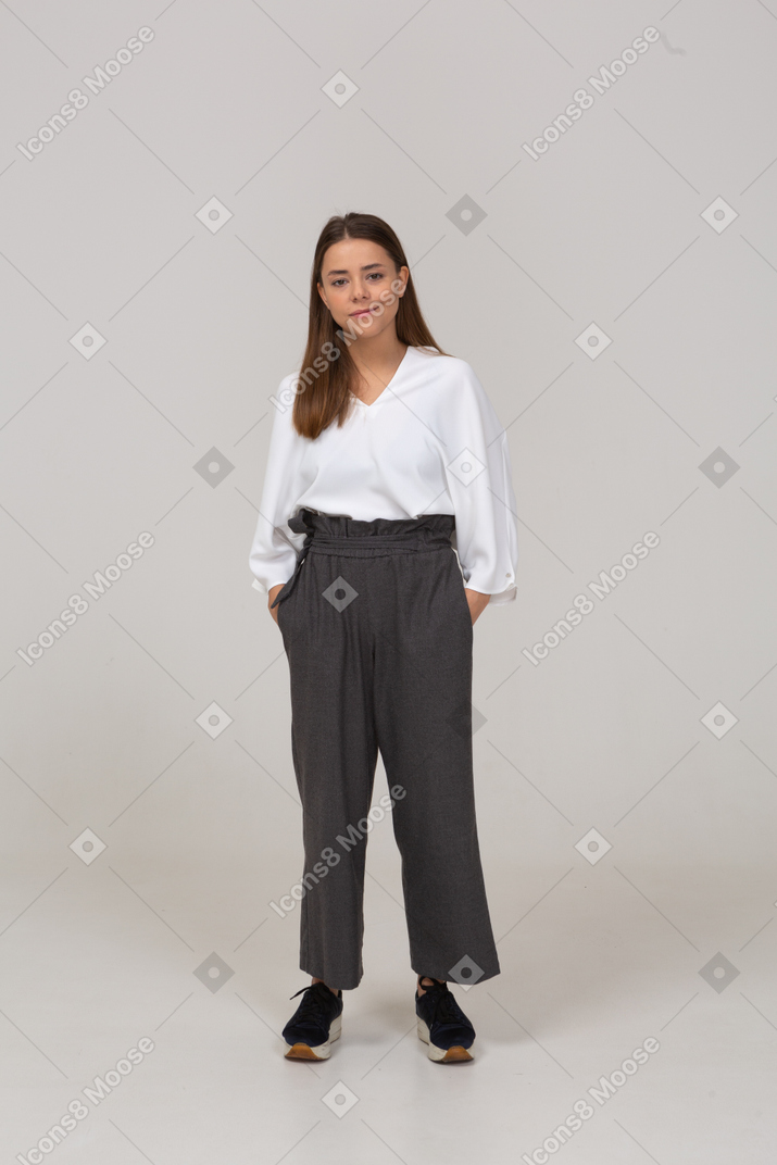 Front view of a smiling young lady in office clothing putting hands in pockets