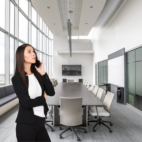 A woman standing in a conference room talking on a cell phone