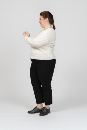 Mulher gorducha em suéter branco mostrando um coração com os dedos