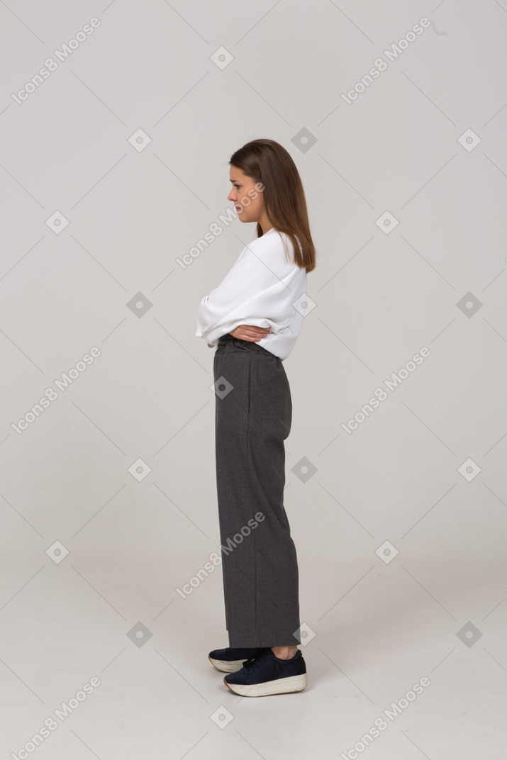 Side view of an upset young lady in office clothing embracing herself