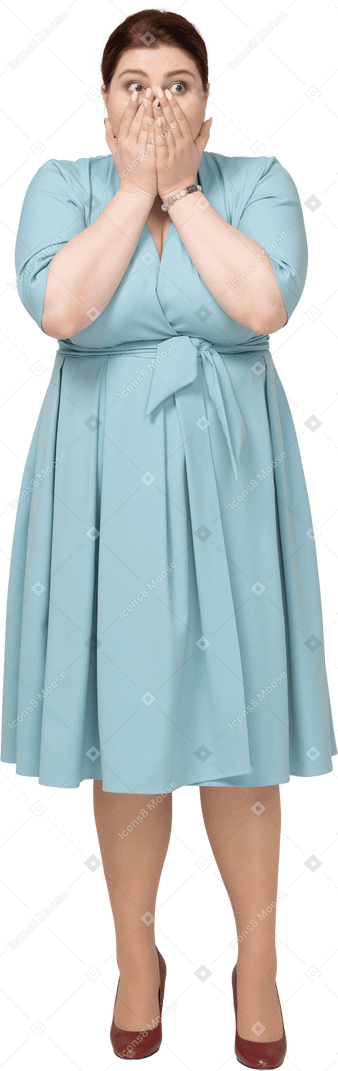 一位身穿蓝色连衣裙、用手捂住嘴的震惊女人的正面图