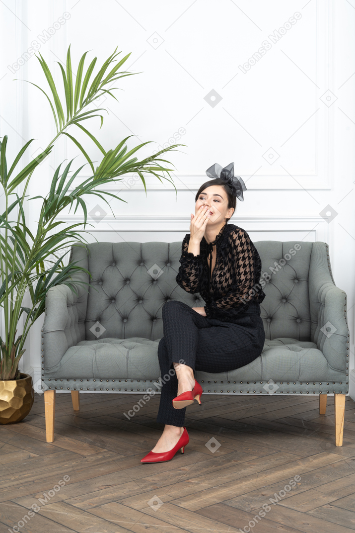 A young woman sitting on a couch and looking at the camera