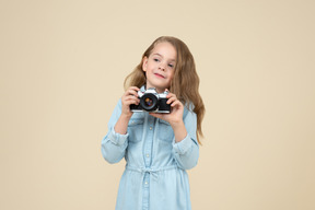 Bambina carina che tiene una macchina fotografica