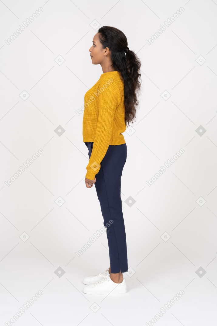 Chica en camisa amarilla de pie en el perfil