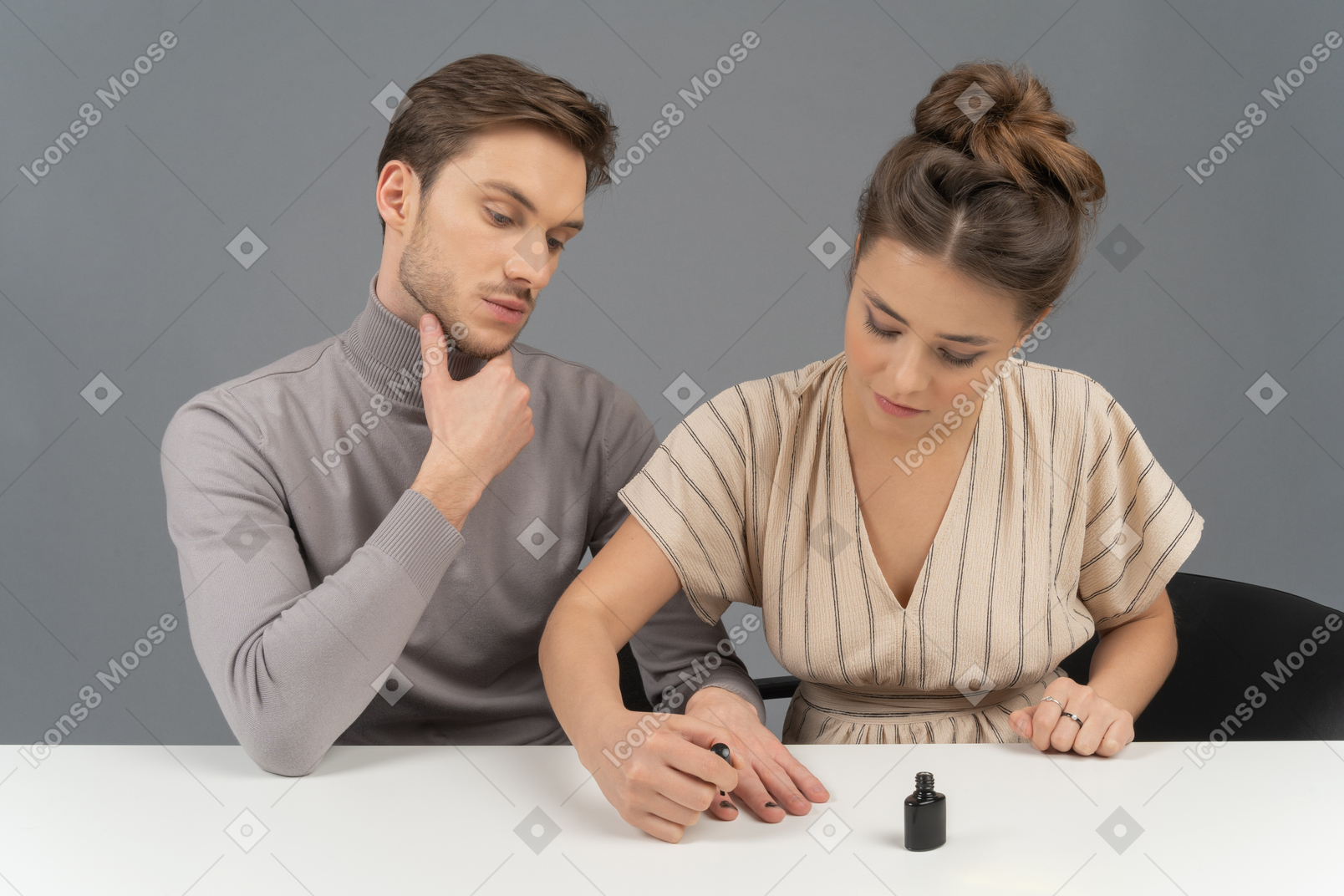 A young woman polishing her husband`s nails
