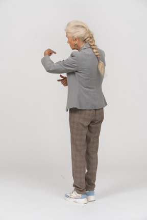 Vista traseira de uma senhora idosa de terno mostrando a direção certa