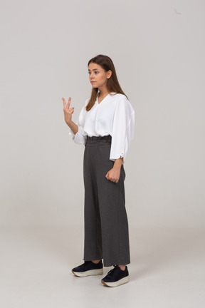 Three-quarter view of a young lady in office clothing showing two fingers