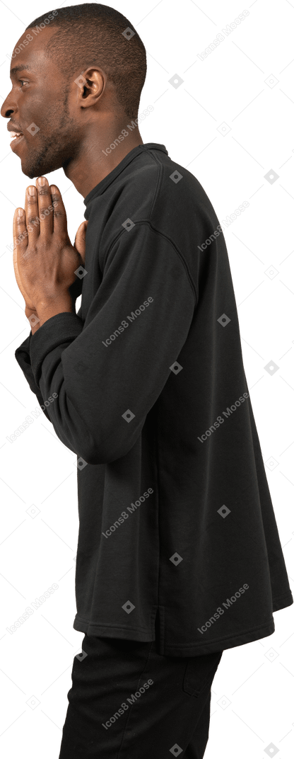 Vista laterale di un uomo con le mani in preghiera