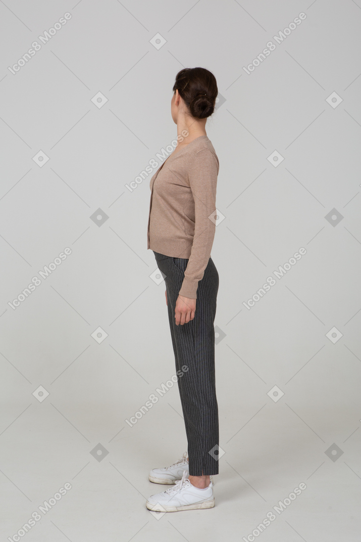Vista lateral de uma jovem de pulôver e calças virando-se