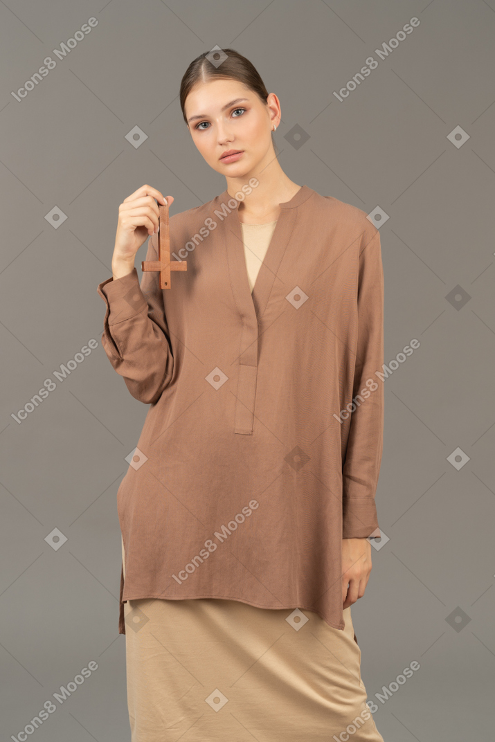 Young woman holding back view cross