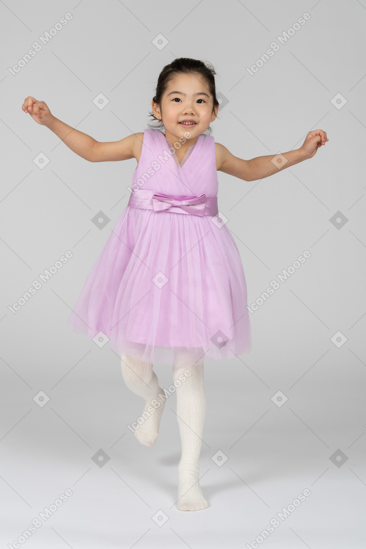 Girl in a pink dress jumping on one leg