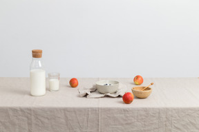 Bottle of milk, glass og milk, red apples and bowls