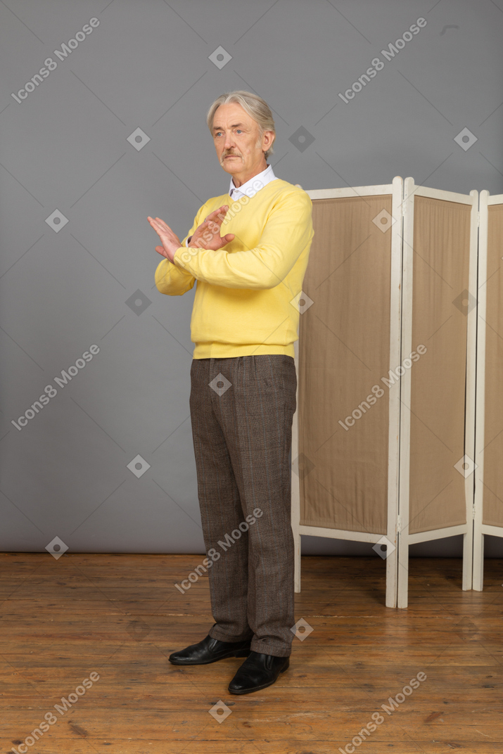 Vista laterale di un uomo anziano riluttante che attraversa le mani