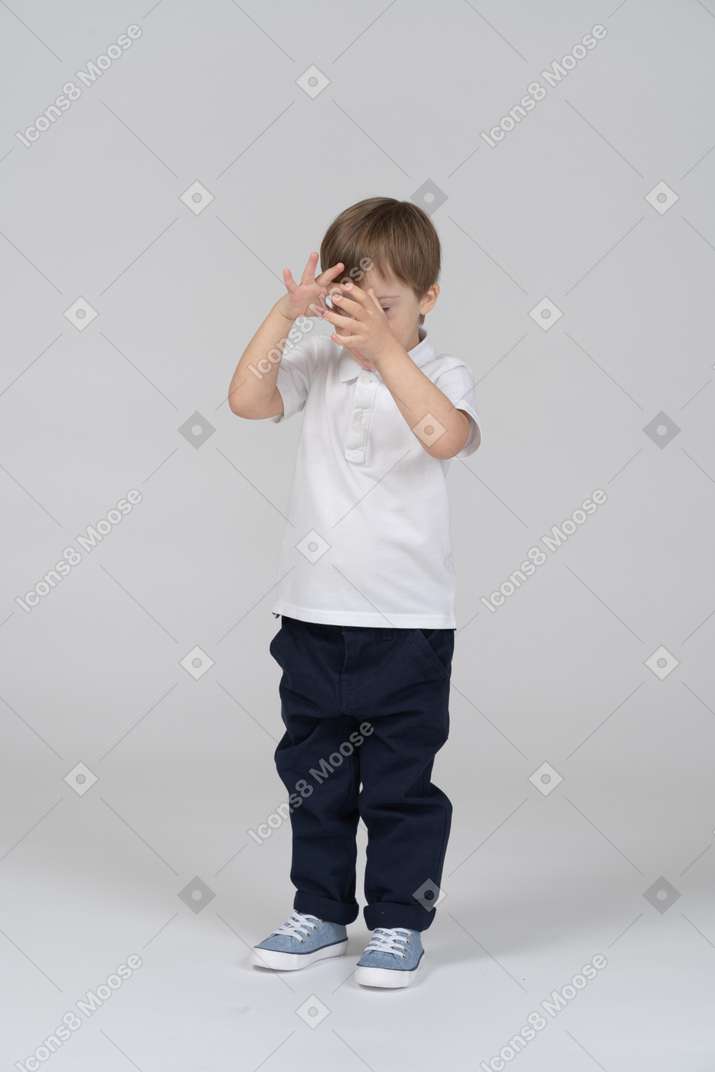 Vista frontal de un niño pequeño que cubre su rostro