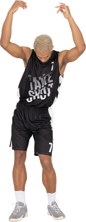 Front view of a young male basketball player raising hands while looking down