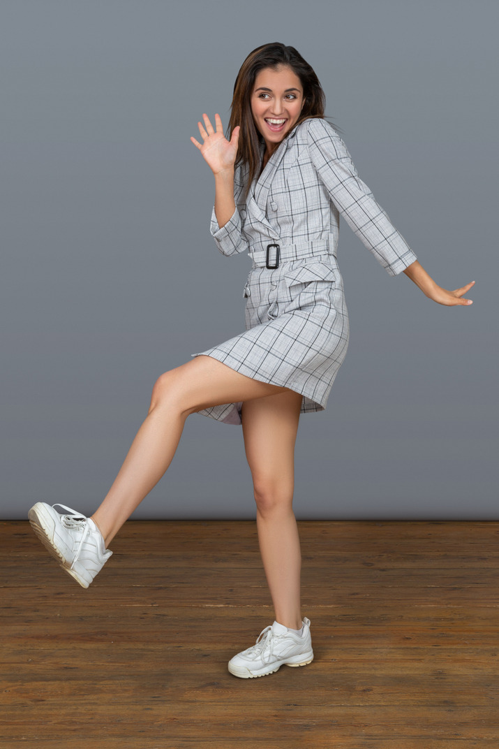 Cute cheerful young woman balancing on one leg