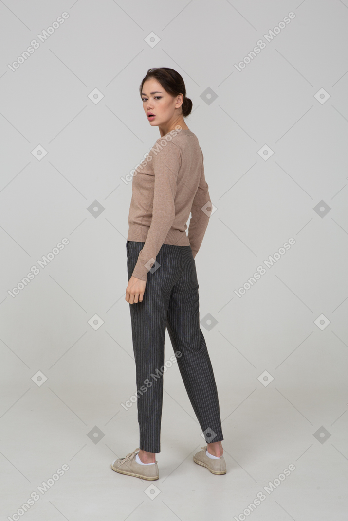 Vista posteriore di tre quarti di una giovane donna preoccupata in maglione e pantaloni che si allontana