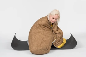 Mature woman sitting on yoga mat wrapped in blanket