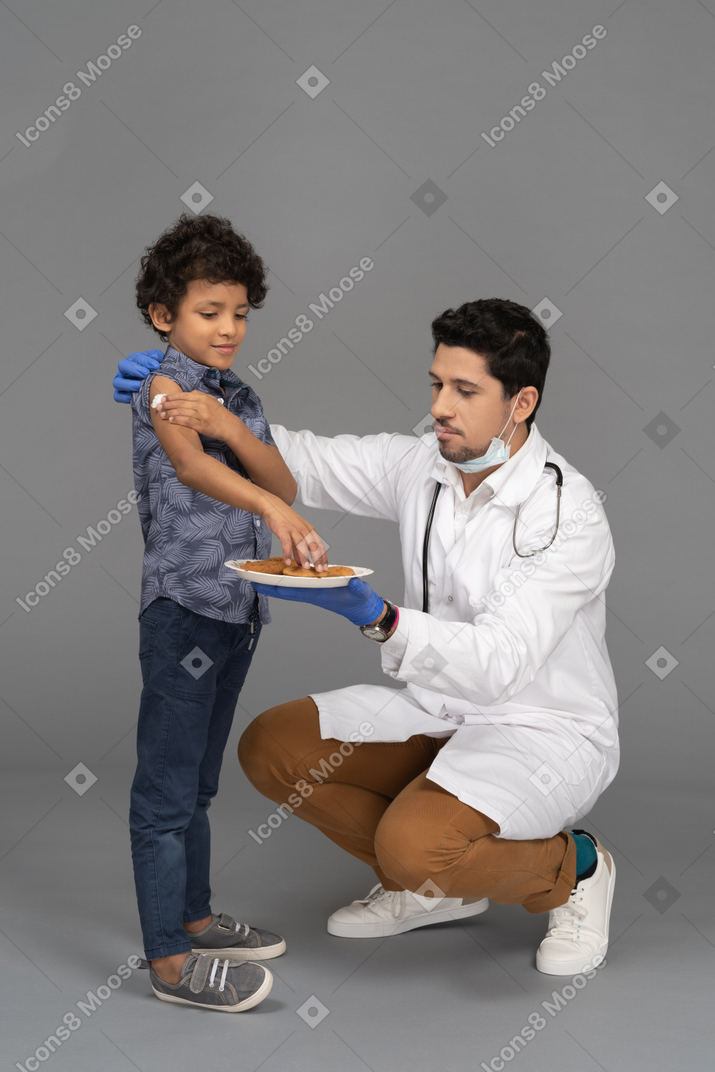 医生在接种疫苗后给男孩吃饼干