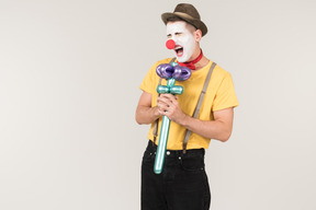 Male clown singing using balloon flower like a microphone