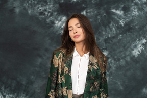 Retrato frontal de una joven mujer satisfecha en chaqueta de seda