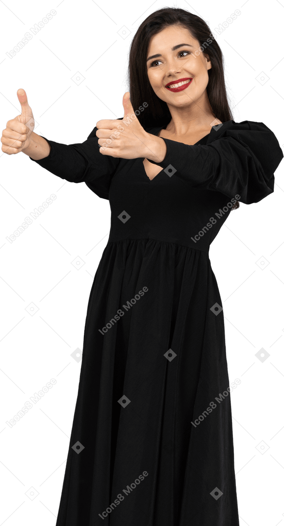 Vista di tre quarti di una giovane donna in un abito nero che mostra i pollici in su