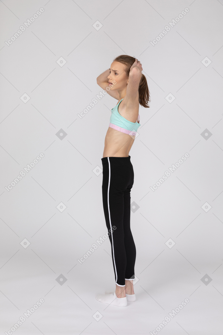 Side view of a worried teen girl in sportswear touching her head