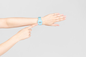 Main féminine pointant sur la montre bleue sur une autre main